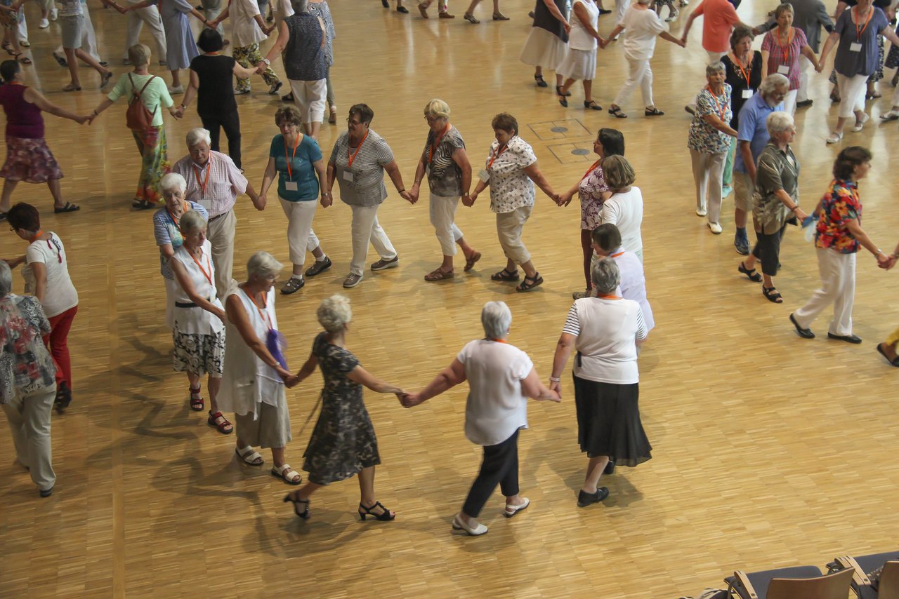 Menschen beim Tanzfest bilden einen Kreis und halten sich an den Händen