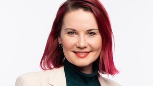 Portrait Straub: Eine junge Frau mit rötlichem schulterlangem Haar. Sie trägt einen schwarzen Rollkragenpullover und einen hellen Blazer.