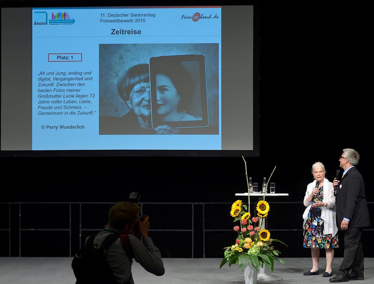 Two persons on stage during award ceremony of the photo competition