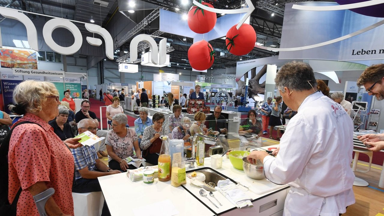 IN FORM Stand von hinten mit Blick ins Publikum: Am Stand kocht gerade ein Mann in Kochkleidung.