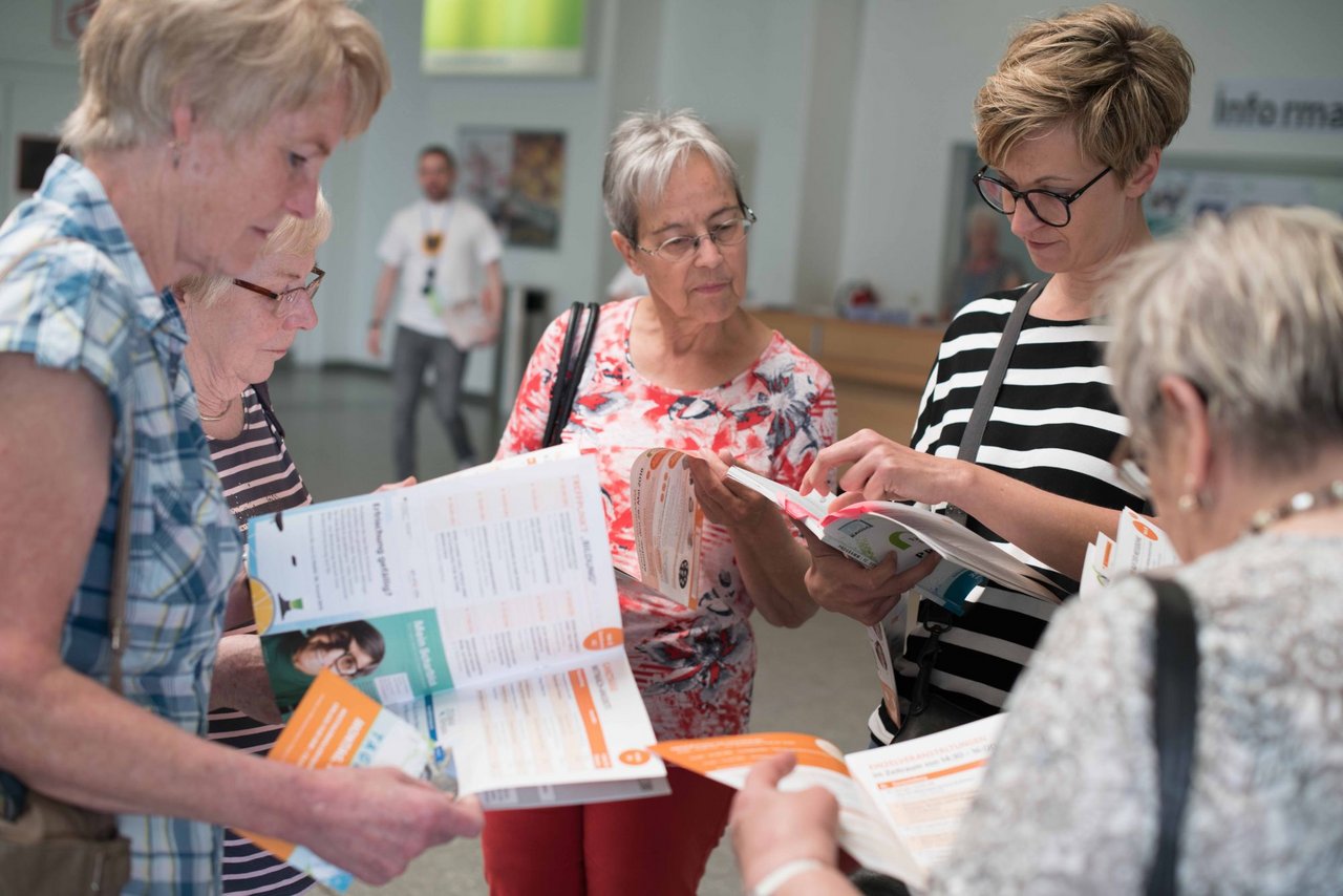 Besucherinnen lesen sich das Programm des Deutschen Seniorentags durch.