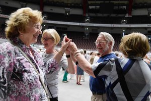 Drei Frauen und ein Mann tanzen im Kreis und halten sich in der Mitte an den Händen.
