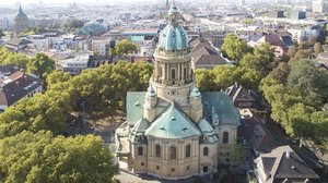 © Johannes Vogt Die Mannheimer Christuskirche mit großer Kuppel und türkisen Dächern aus der Vogelperspektive. Die Kirche ist umringt von Bäumen.