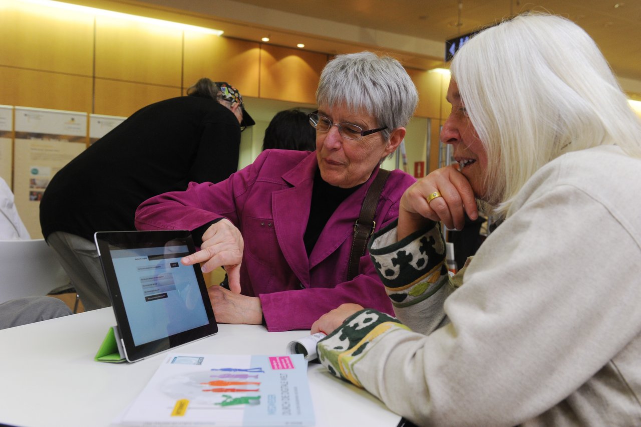 A woman explains something to another woman on the tablet