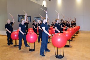 © BAGSO/Hoffmann Gruppenfoto von Menschen, die im Stehen auf einem Gymnastikball trommeln