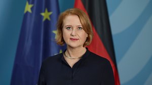 Porträtfoto der Bundesministerin für Familie, Senioren, Frauen und Jugend, Lisa Paus: Eine blonde Frau mit kinnlangen Haaren steht vor den Flaggen von Deutschland und Europa.