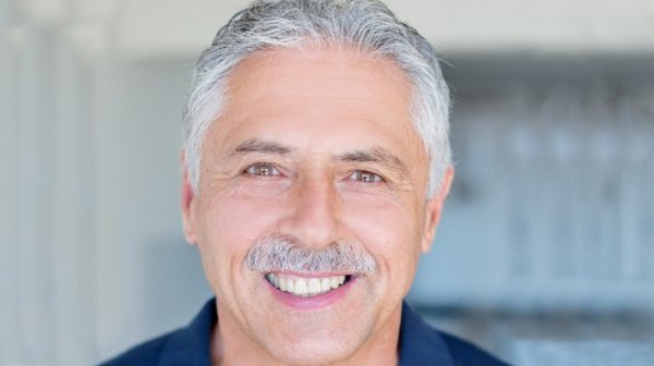 Ein Mann mit grauen Haaren und Schnauzbart.