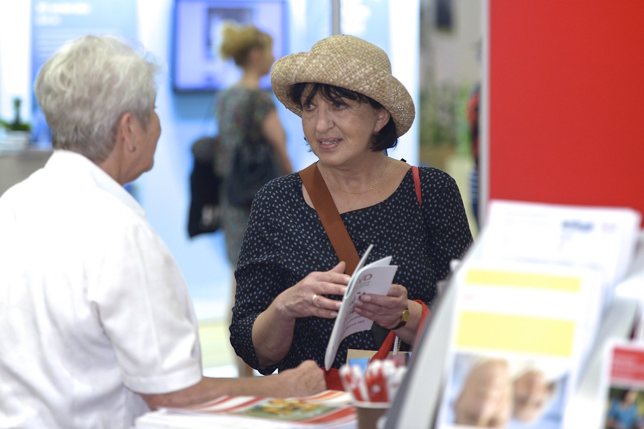 Frau mit Strohhut wird an einem Messestand beraten