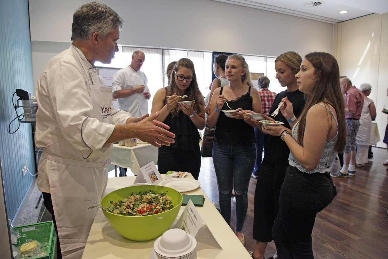 Koch spricht mit mehreren jungen Frauen, die Essen in den Händen halten